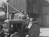 Auf dem Bild sieht man das Jahr 1959. Im Vordergrund sieht man eine Traktor der Marke Eicher. Auf dem Traktor sitzen Opa Heinrich und der dreijährige Heinfried Peth.